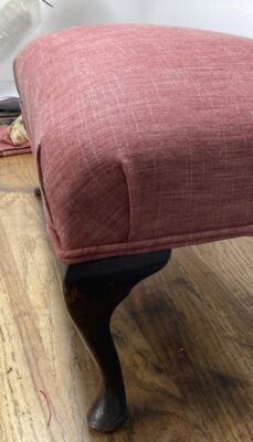 A photo from the upholstery course at Farnham School of Furniture. It shows a covered footstool.