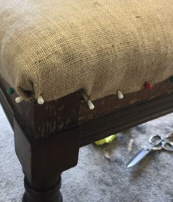 A photo from the upholstery course at Farnham School of Furniture. It shows a footstool being covered.