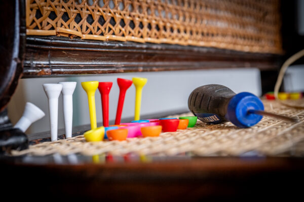 A photo from the chair caning course at Farnham School of Furniture. It shows a chair being caned. There are some golf tees in the picture.
